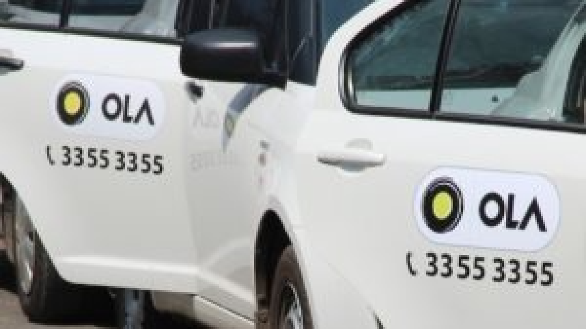 In this photo illustration Ola Cabs logo seen displayed on a smartphone and  in the background Stock Photo - Alamy